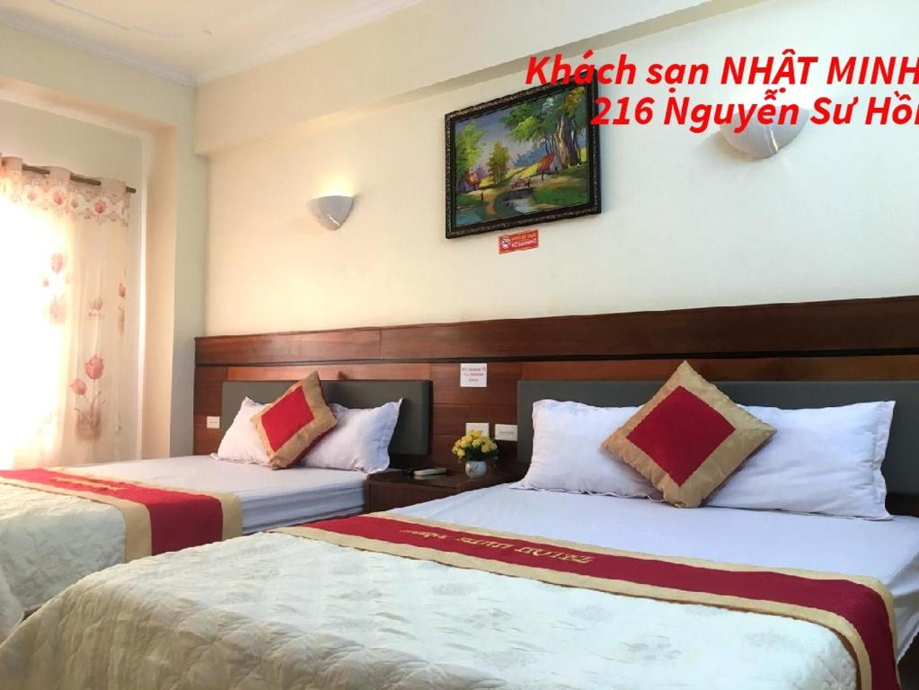 格卢市社Khách sạn NHẬT MINH Cửa Lò的酒店客房设有两张床,墙上有标志