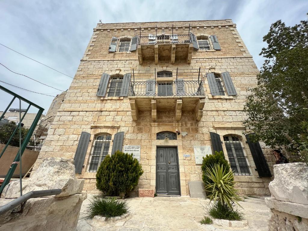 伯利恒Ma'an lil-Hayat Boutique Hotel的一座古老的石头建筑,设有阳台和门