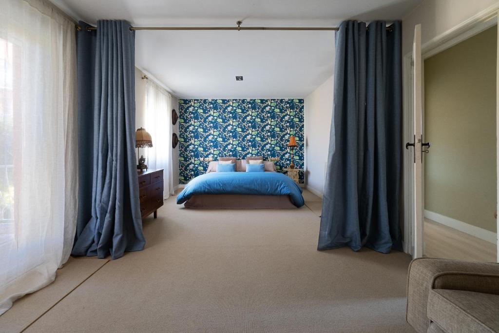 莱昂Casa Palomera - Casa completa con jardín, gimnasio y garaje privados的一间卧室配有蓝色的床和蓝色窗帘