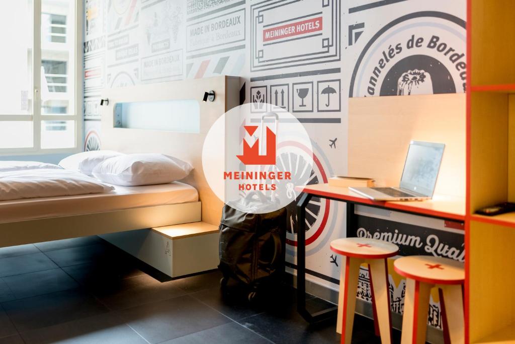 波尔多MEININGER Hotel Bordeaux Gare Saint-Jean的客房设有一张床、一张桌子和一台笔记本电脑