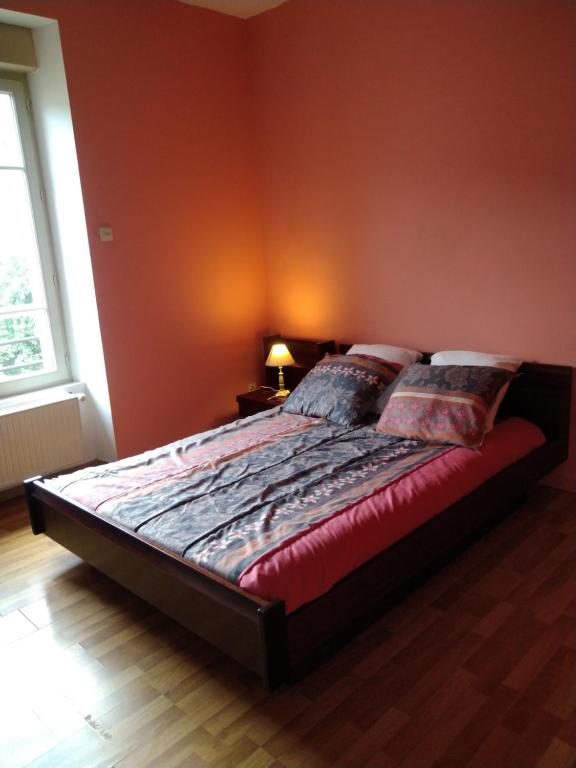 马尔沃若勒Les Chambres de Marvejols的卧室内的一张床位,卧室设有红色的墙壁
