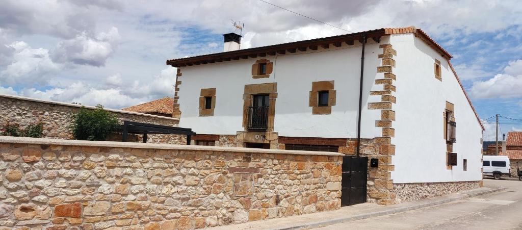 FuentecantosCasa del Medio的一座白色的建筑,旁边是石墙