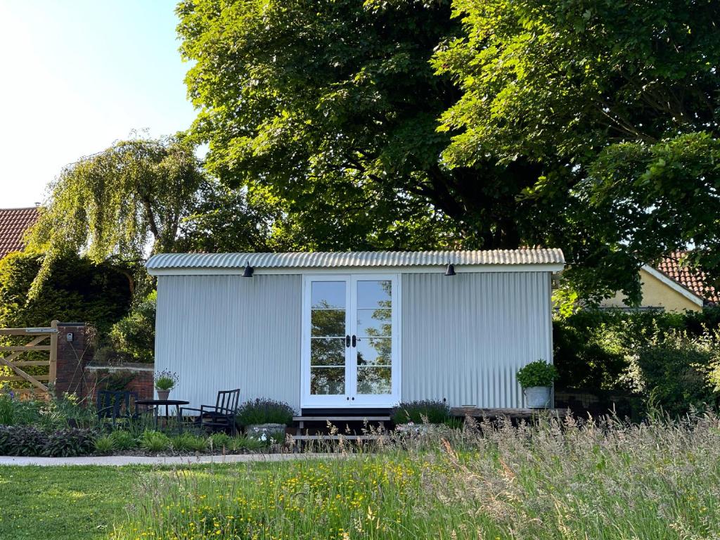 杜伦Self-catering shepherds hut with private garden in Durhams idyllic countryside的院子中带长凳的小白色棚子