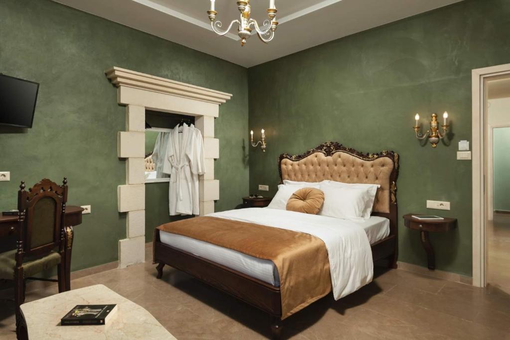 干尼亚Nobili Boutique Hotel的一间卧室配有一张带绿色墙壁和吊灯的床。