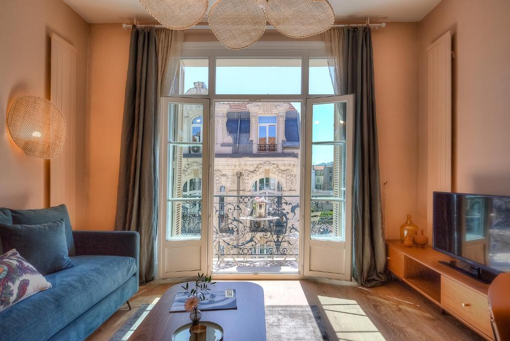 尼斯Maison Lamartine - Nice的客厅设有蓝色的沙发和大窗户