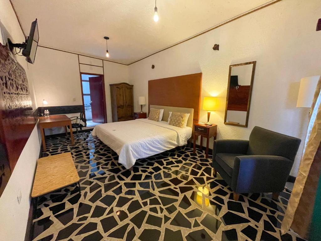 乔卢拉Hotel Vitorina Cholula的一间卧室配有一张床、一张沙发和一把椅子
