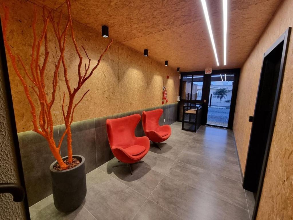 伊达贾伊APTO Studios的大堂设有两把红色椅子和一棵树