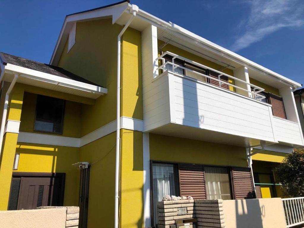 千叶homelike / Vacation STAY 33817的黄色和白色的房子设有阳台