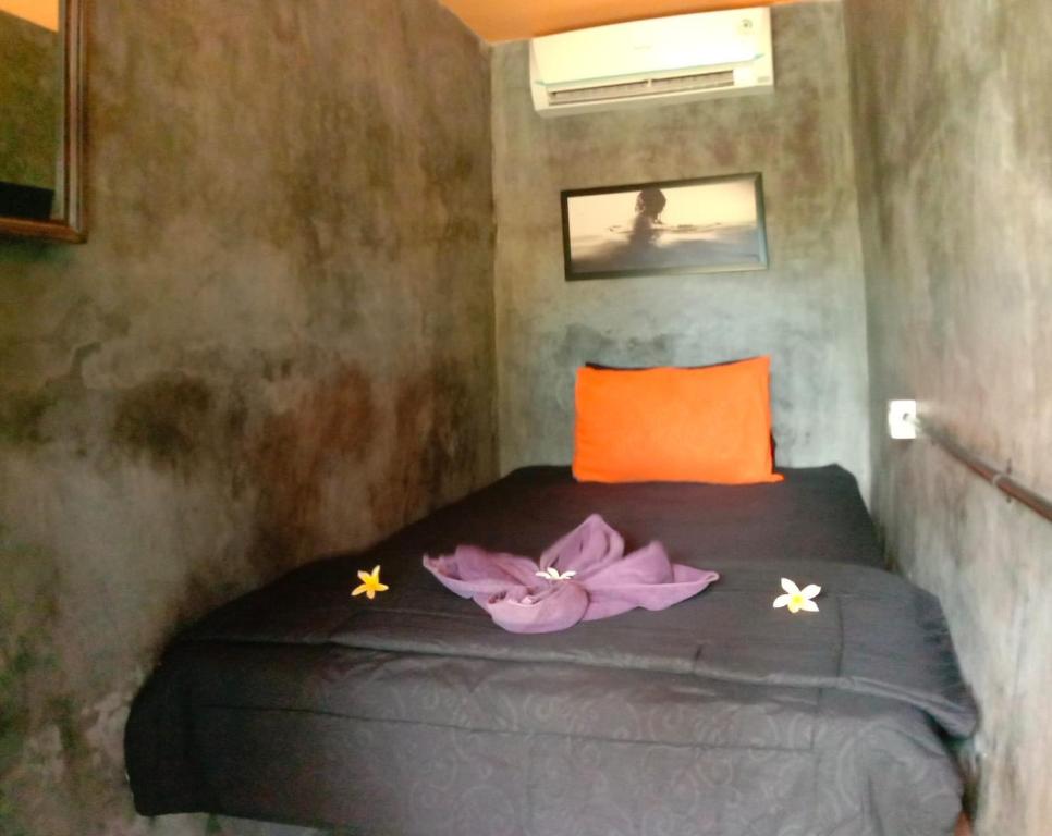 克拉玛斯Keramas Surf Hostel的一间卧室,床上有紫色鲜花