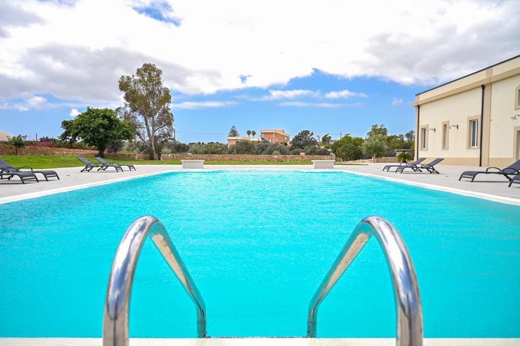 马尔扎梅米Dimora Savarino Marzamemi Suites with pool的一个带蓝色水和金属栏杆的游泳池