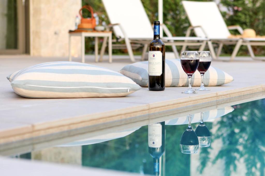 康托卡利My Mediterranean Corfu Luxury Villa with Private Swimming Pool的两杯酒坐在游泳池旁的桌子上
