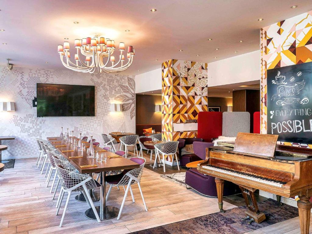 巴黎巴黎蒙马特圣心大教堂美居酒店的一间设有钢琴和桌椅的餐厅