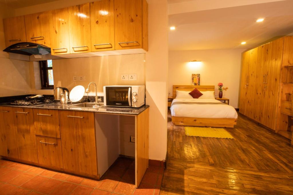 帕坦Patan Wittys hotel的一间卧室配有一张床,厨房配有微波炉