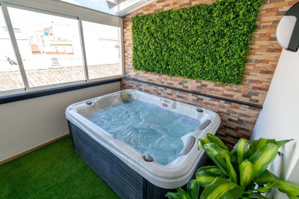 桑卢卡尔-德巴拉梅达Cabildo Spa 1的绿色树 ⁇ 的房间内的热水浴缸
