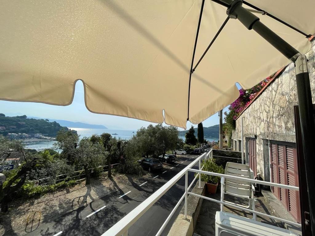 韦内雷港Monolocale Baia dei Delfini的阳台的天井配有遮阳伞和椅子