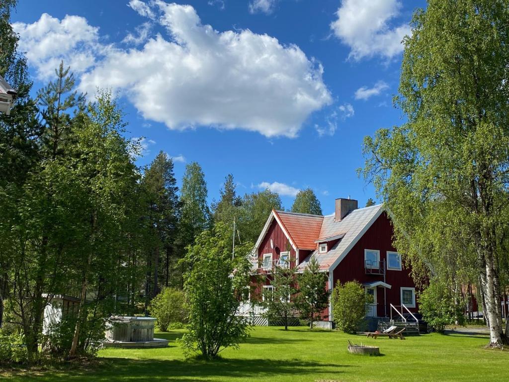 GargnäsNaturResort Änglagård的一座大型红色房子,有草地庭院和树木