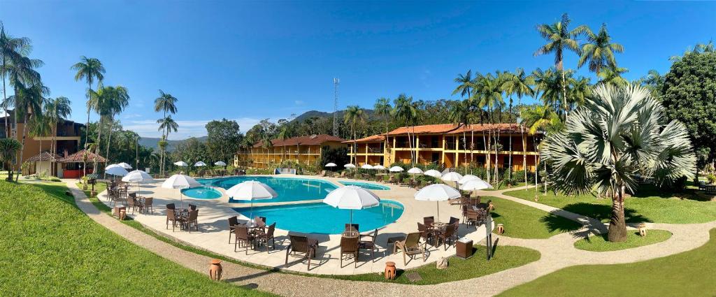 南雅拉瓜Hotel Fazenda Vale das Pedras的一个带椅子和遮阳伞的游泳池的度假酒店