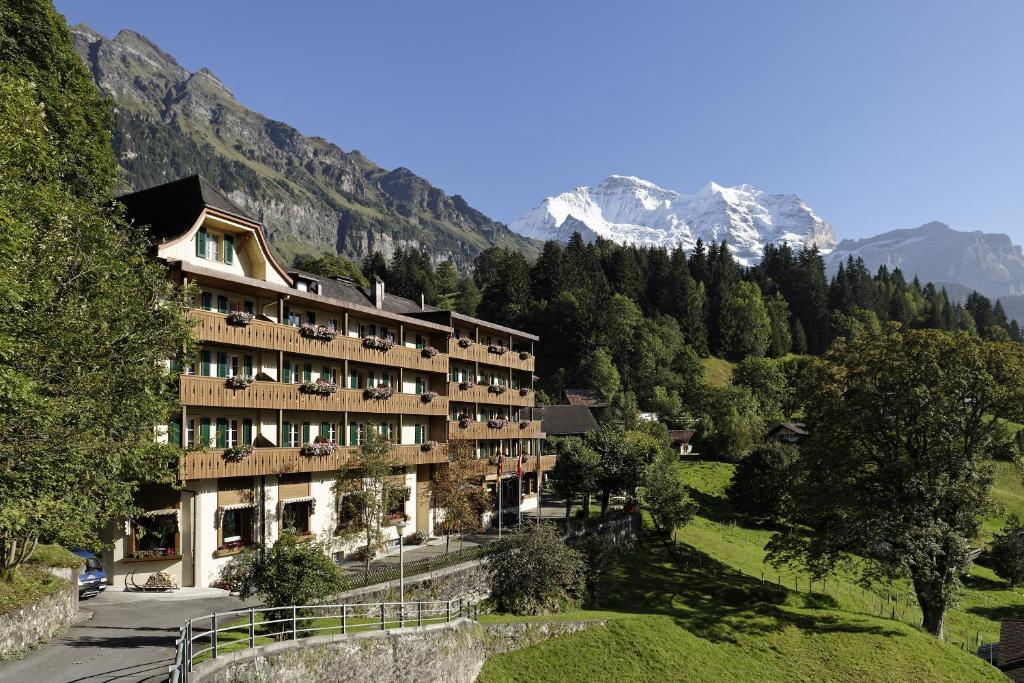 翁根Hotel Alpenrose Wengen - bringing together tradition and modern comfort的山丘上以山为背景的酒店