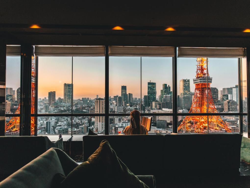 东京The Prince Park Tower Tokyo - Preferred Hotels & Resorts, LVX Collection的一位女人看着艾菲尔铁塔的窗户