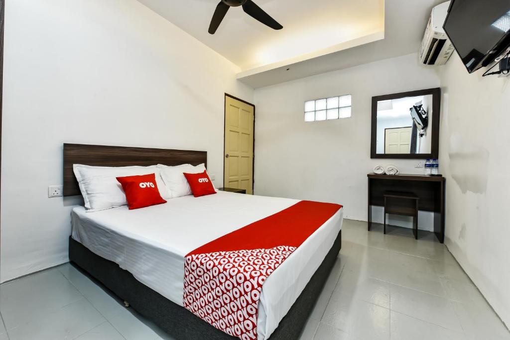 艾尔克如Super OYO 90509 Usima Forest Resort的一间卧室配有一张带红色枕头的床和一张书桌