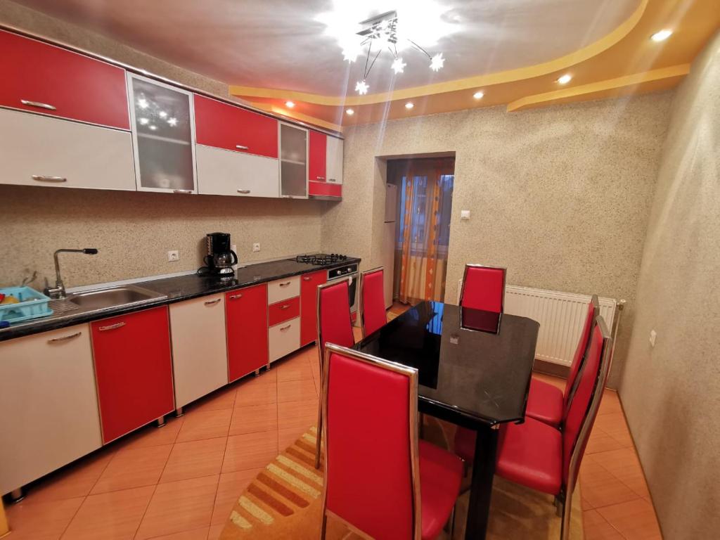 阿尔杰什河畔库尔泰亚Apartament Patrick的厨房配有红色橱柜和桌椅