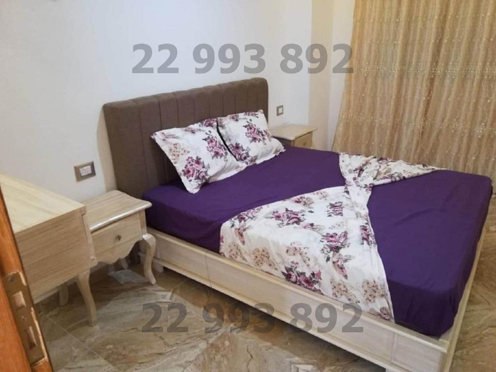 古莱比耶S 2 1km from the beach in Kelibia的一间卧室配有一张带紫色床单的床和一张书桌。