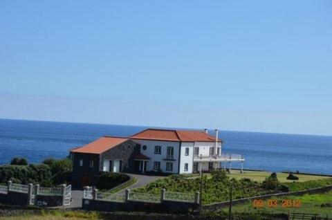 英雄港Vivenda da Saudade B&B的一座白色的房子,在田野顶部有红色屋顶