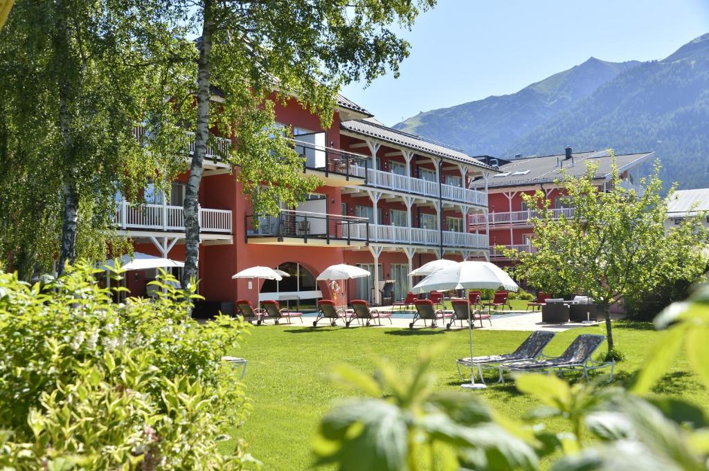 蒂罗尔-泽费尔德Das Hotel Eden - Das Aktiv- & Wohlfühlhotel in Tirol auf 1200m Höhe的前面设有桌子和遮阳伞的酒店