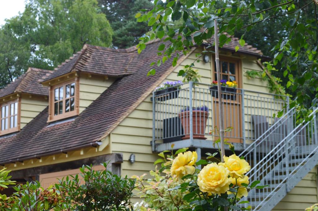 斯托灵顿Pinecroft Barn - Relax & Unwind!的黄色的房子,设有阳台和黄色玫瑰
