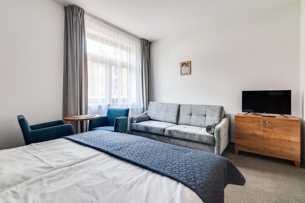 斯克拉斯卡波伦巴彭斯约纳特里德酒店的一间卧室配有一张床、一张沙发和一台电视