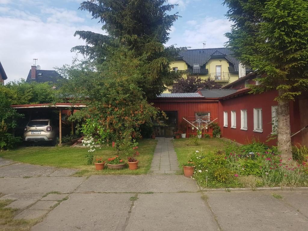 库瑞尼卡慕斯卡Pokoje Rybacka 5的一座带红房子的院子,里面种有盆栽植物