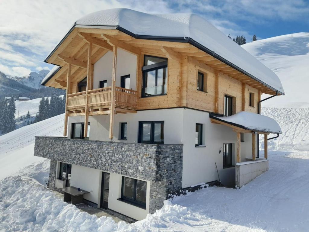 瓦格赖恩Appartement Kuschelzeit Jansenbichl的雪覆盖的山顶上的房子