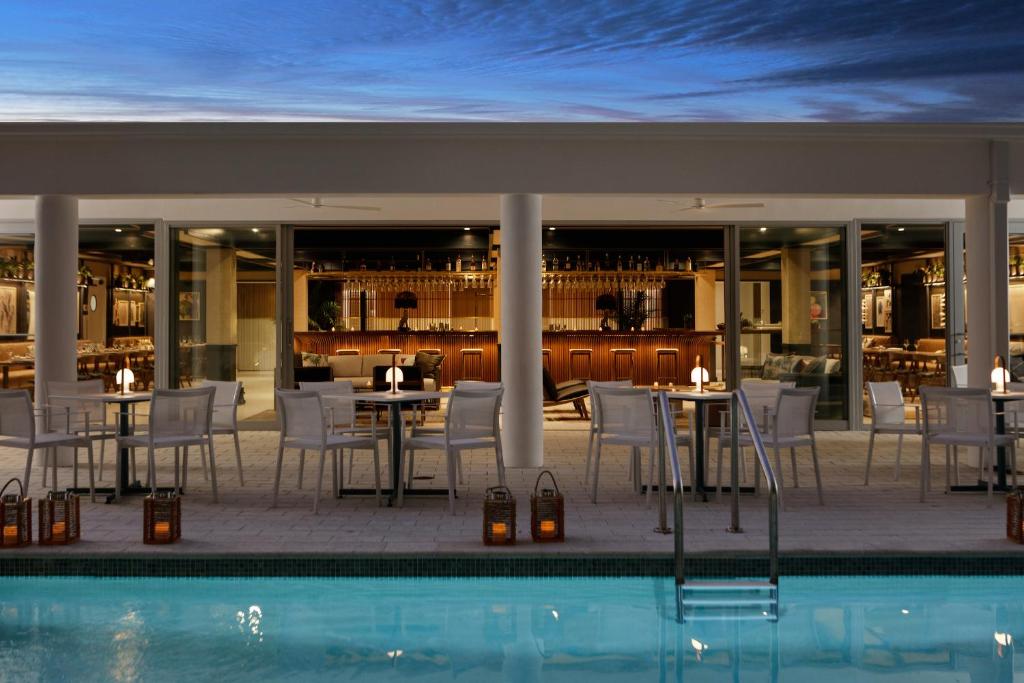 劳德代尔堡The Kimpton Shorebreak Fort Lauderdale Beach Resort的游泳池位于餐厅前,配有桌椅