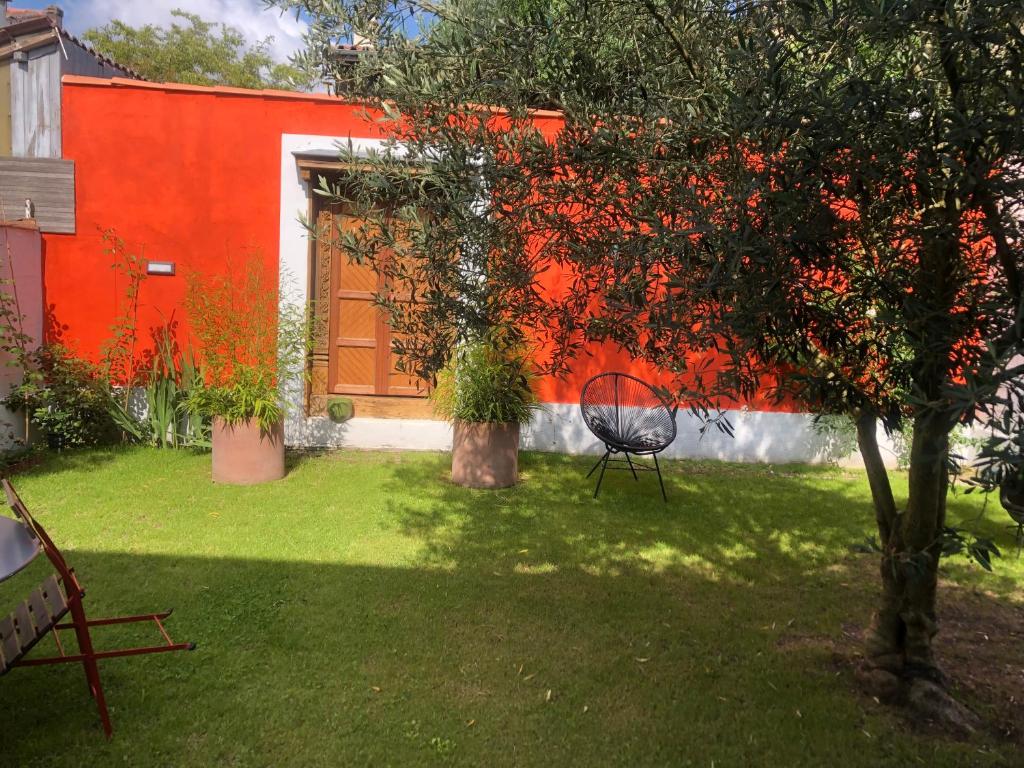 波尔多CHAMBRES chez l'habitant Córdoba et Lhassa的花园,花园内有红色的墙壁,院子内有椅子