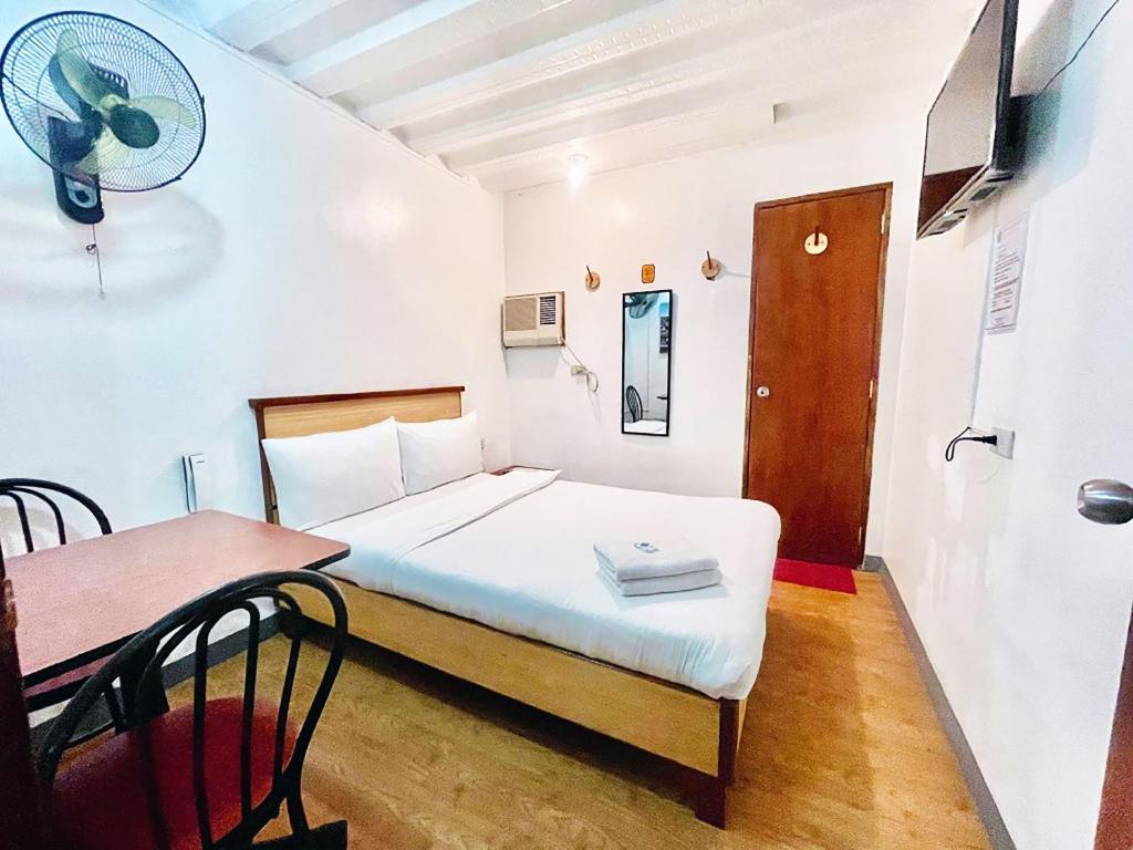 马尼拉Marion Hotel的一间卧室配有一张床和一张带风扇的桌子。