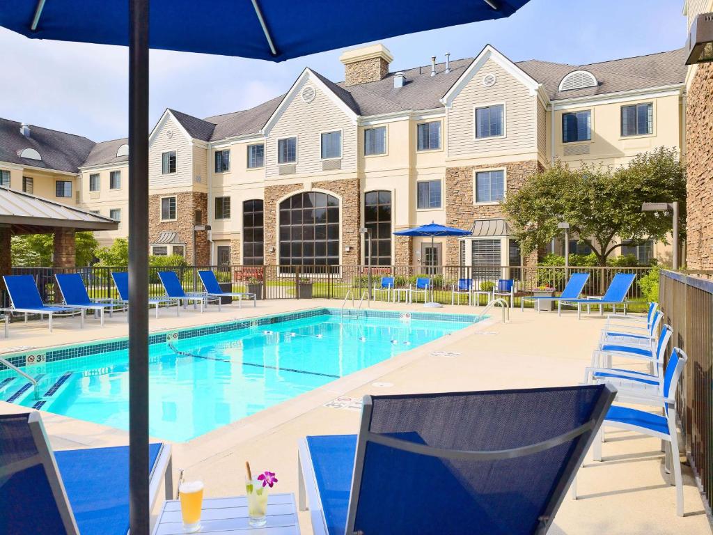 休斯顿休斯顿盖乐瑞圣淘沙ES套房酒店的一座带蓝色椅子的游泳池和一座建筑
