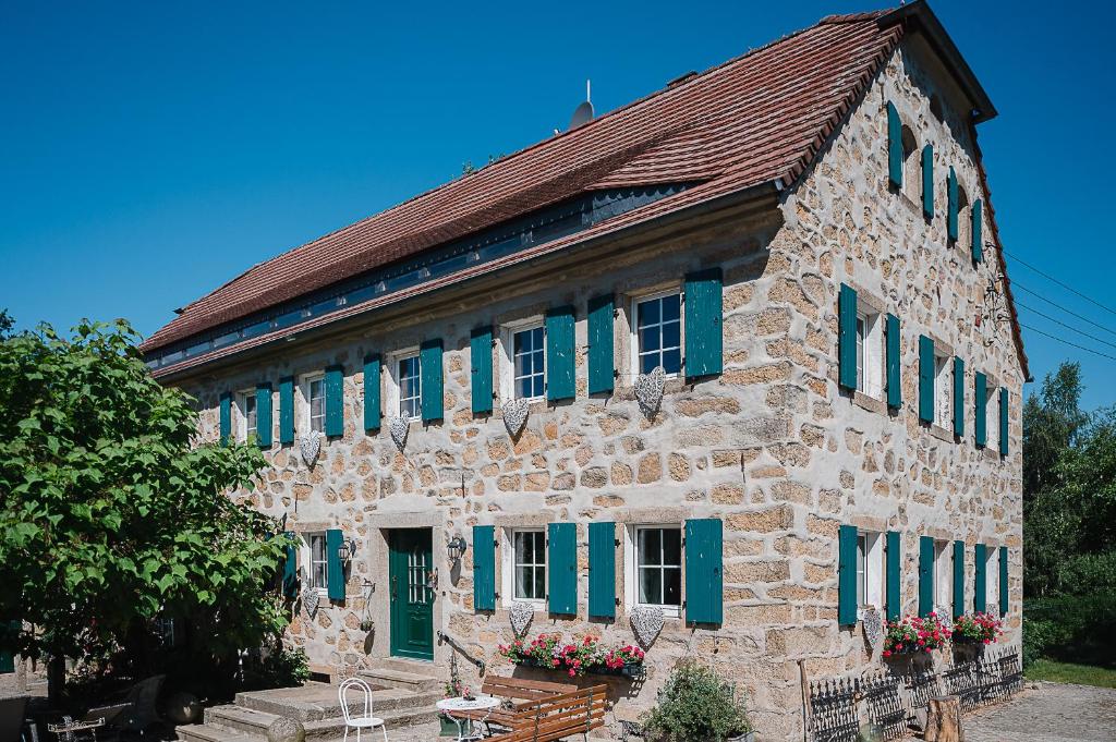 ArnsdorfIdyllischer Bauernhof mit viel Charme的一座带绿色百叶窗的大型石头建筑