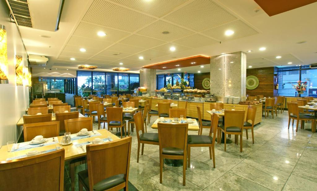 福塔莱萨迪奥戈酒店的一间带木桌椅的餐厅和一间酒吧