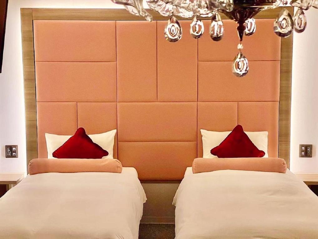 大阪Doutonbori Crystal Hotel的两张位于酒店客房的床铺,配有红色枕头