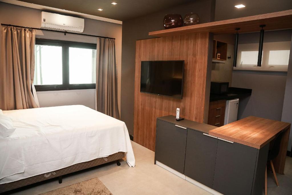 里梅拉Globo Lar Studios的一间卧室配有一张床和一台平面电视