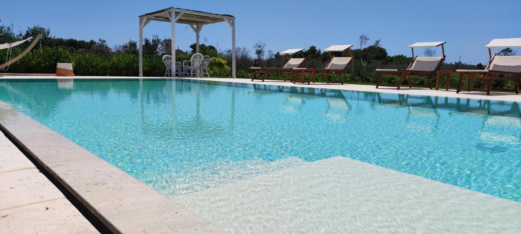 乌贾诺拉基耶萨Masseria Vignenove的一个带椅子和蓝色水的大型游泳池