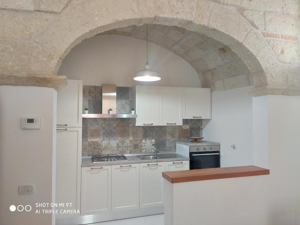 滨海波利尼亚诺Casa Di Antonio的厨房配有白色橱柜和石墙