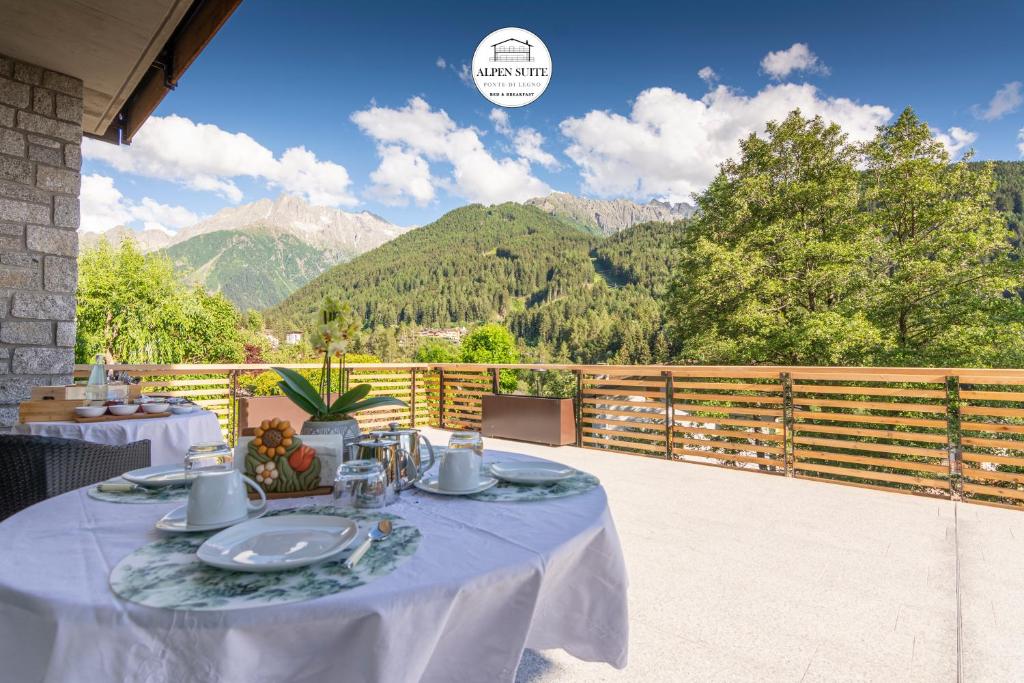 蓬泰迪莱尼奥B&B Alpen Suite Ponte di Legno的阳台的桌子,背景是山脉