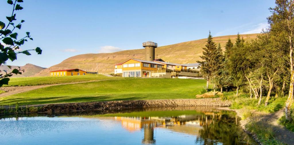 阿克雷里Hotel Natur Akureyri的水体旁山丘上的房屋