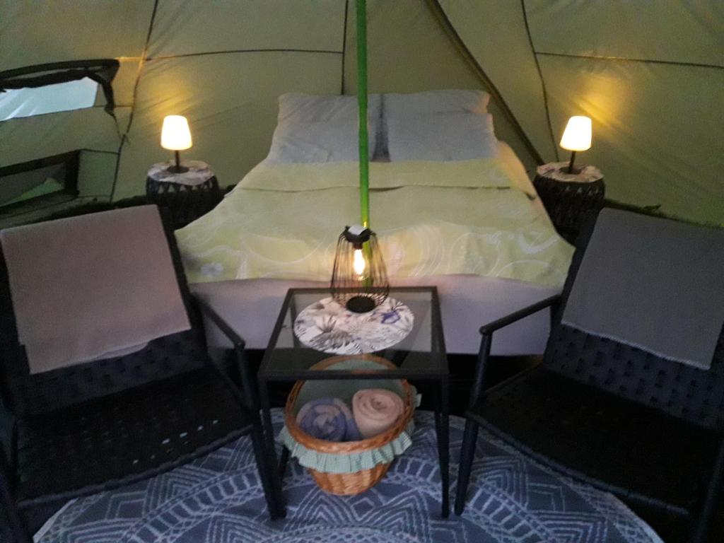 LyngstadLeite Telt Camping的帐篷配有1张床、2把椅子和1张桌子