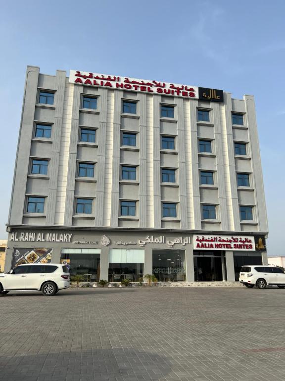 索哈尔Aalia Hotel Suites的一座大型建筑,前面有汽车停放
