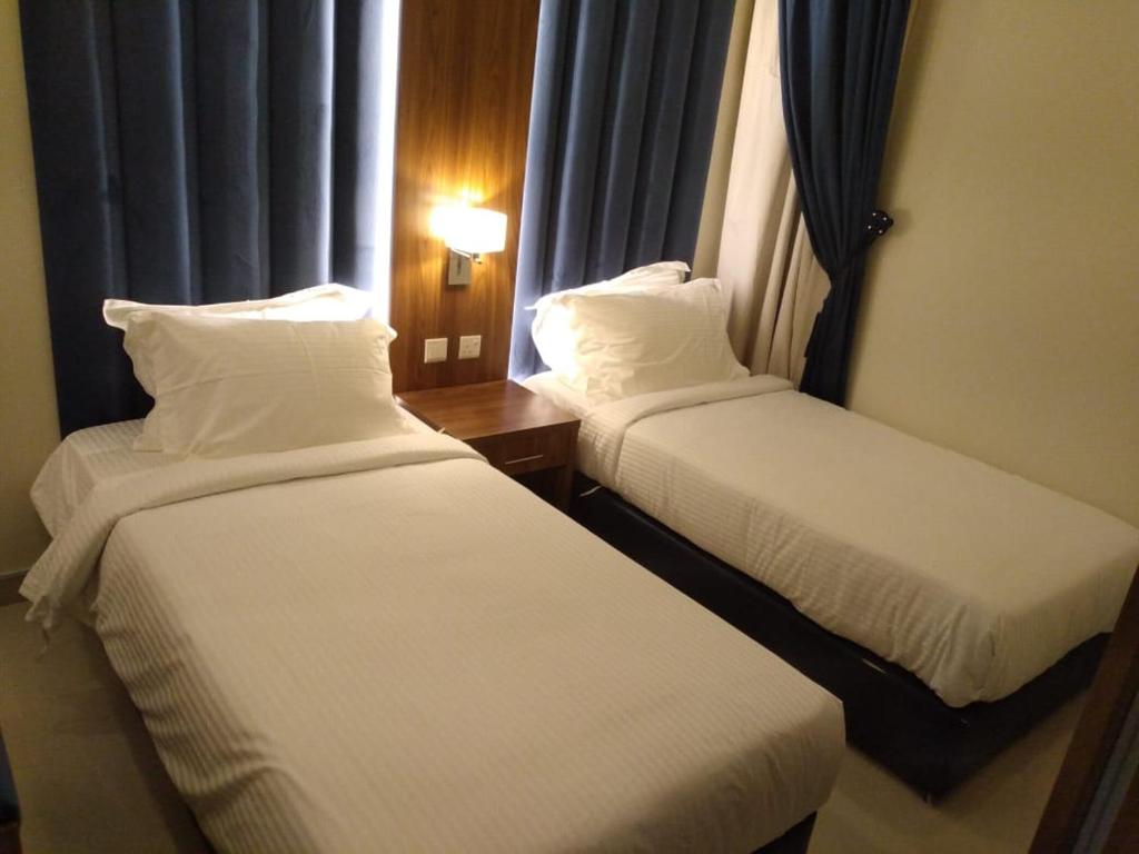 布赖代Reef Al Qassim Hotel Apartments的酒店客房设有两张床和窗户。