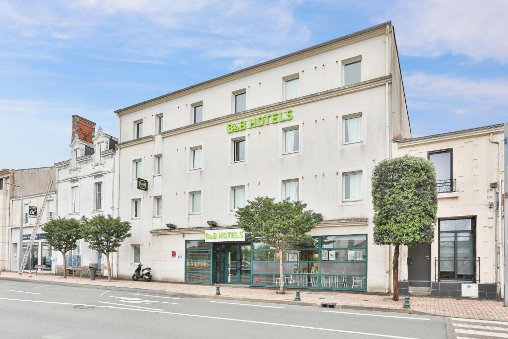 莱萨布勒-多洛讷B&B HOTEL Les Sables-d'Olonne Centre Gare的街上有商店的白色建筑