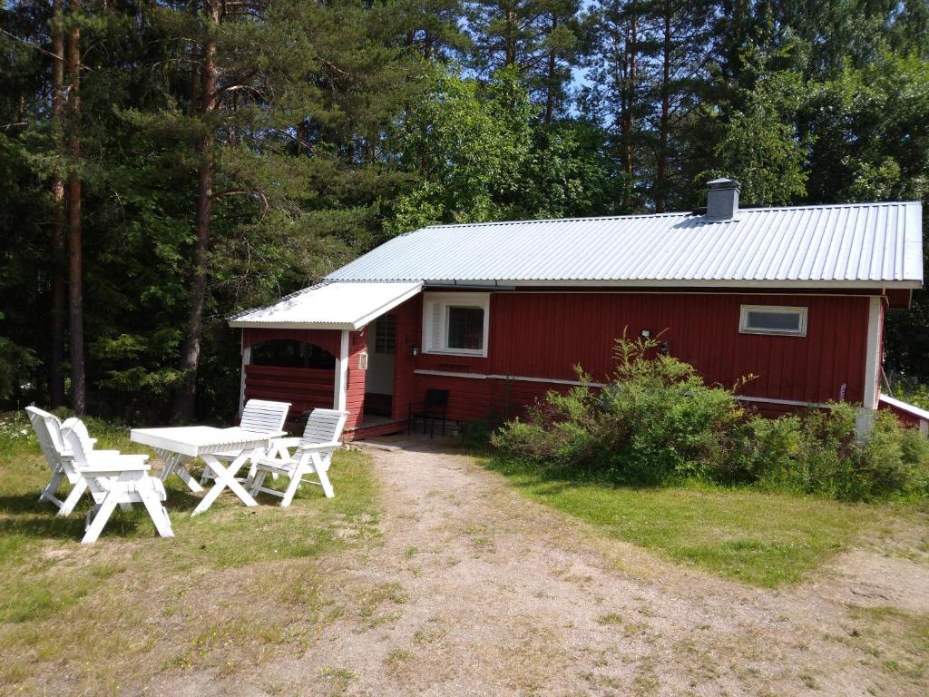 拉彭兰塔Mentulan Cottage的一间红色小屋,前面设有野餐桌和椅子