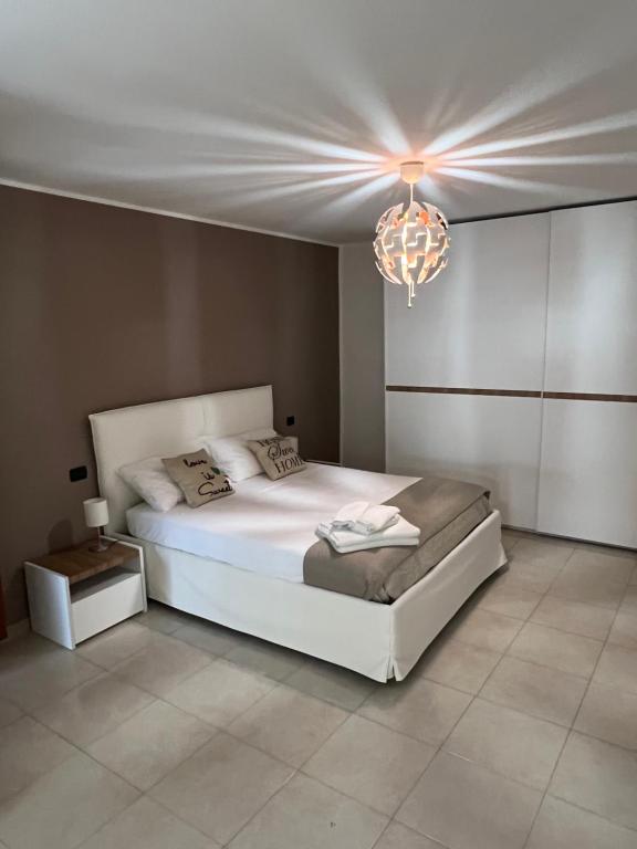 莫诺波利Nial House的卧室配有白色的床和吊灯。